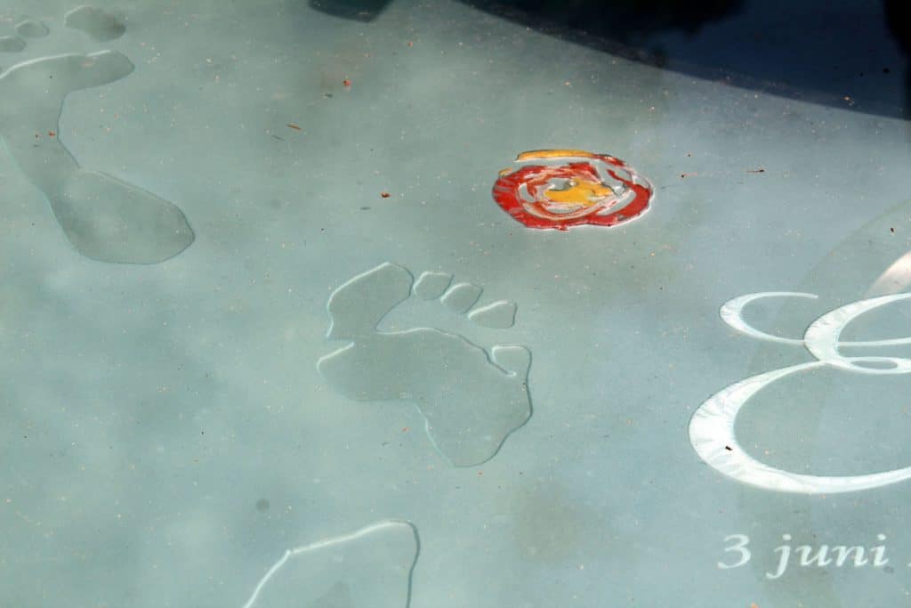 voetafdruk en bloem in glazen grafmonument