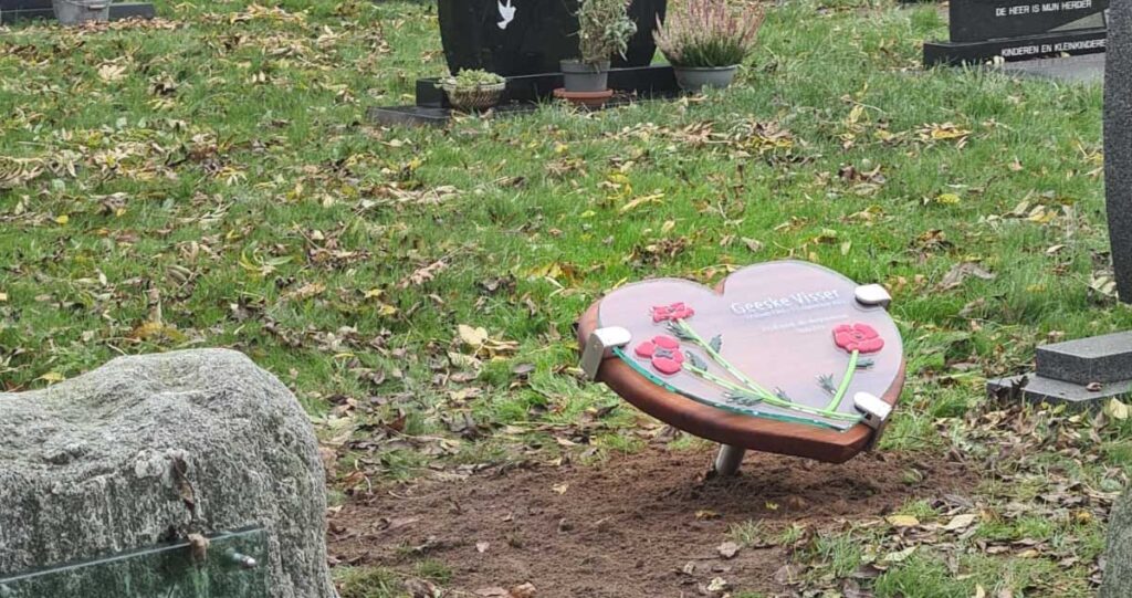 gedenkteken glazen hart met bloemen op begraafplaats