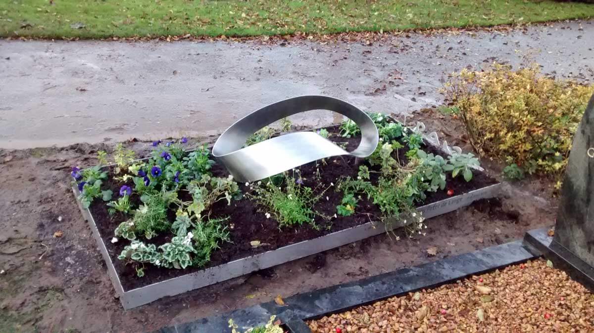 Modern RVS Grafmonument met ring Mobius voor partner met beplanting
