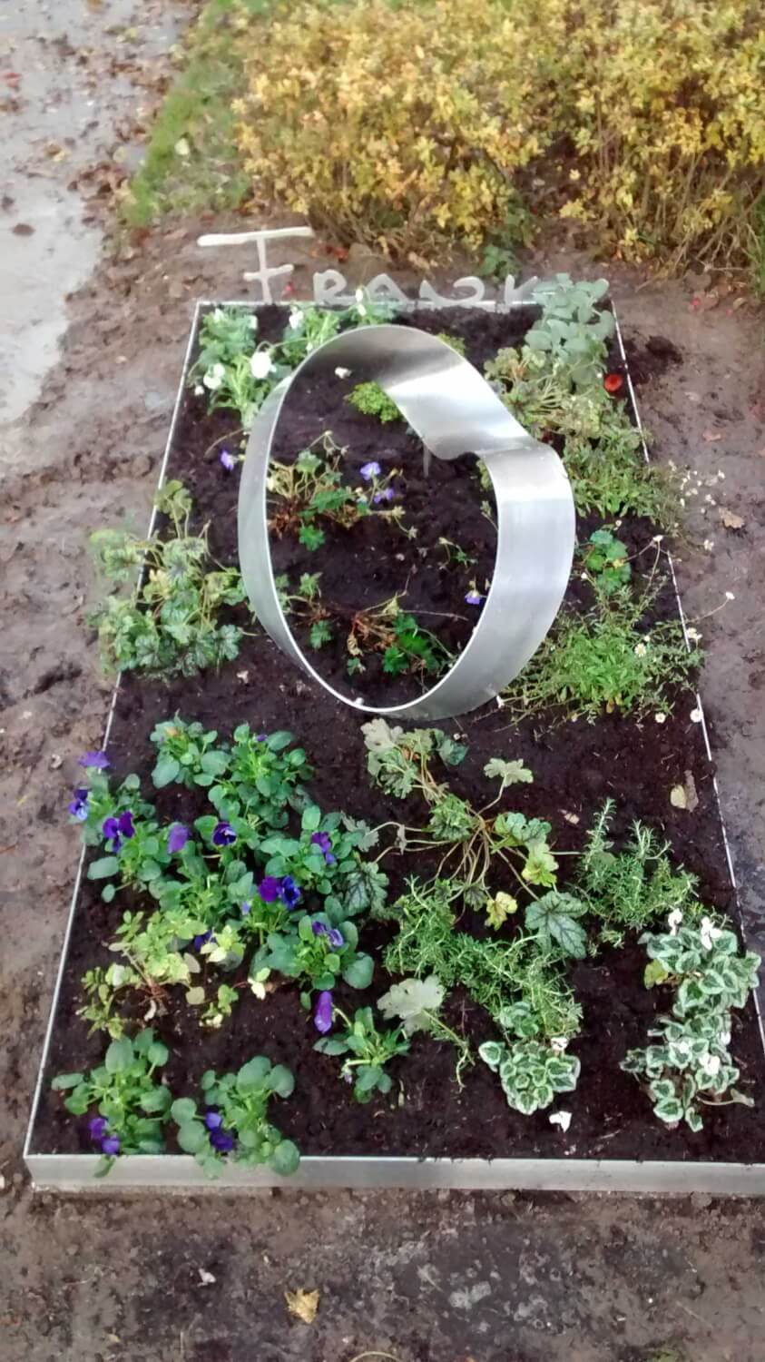 Abstract en eigentijds RVS Grafmonument met ring Mobius voor partner met beplanting