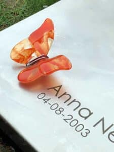 oranje glazen vlinder op grafmonument van een kind