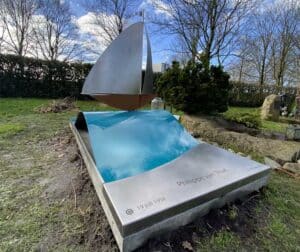 rvs grafsteen met zeilbootje op blauwe golf